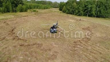 直升机在空中盘旋。 直升机降落在森林带附近的田野上。 直升机降落在黄草上